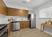 Thumbnail 11 of 31 - A kitchen with wooden cabinets and a stainless steel refrigerator.