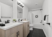 Thumbnail 7 of 38 - A bathroom with a white sink and black tiles.