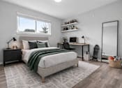 Thumbnail 19 of 33 - A bedroom with a large bed, a desk with a chair, and a window with a view of trees.