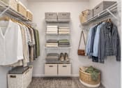 Thumbnail 13 of 24 - A white closet with clothes and baskets.