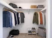 Thumbnail 20 of 31 - A white closet with clothes and shoes.