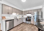 Thumbnail 2 of 47 - a kitchen with stainless steel appliances and wooden floors at Edge At Farmington Hills - Farmington Hills, MI, Michigan