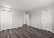 Thumbnail 28 of 34 - an empty living room with white doors and wood flooring