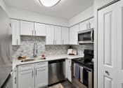Thumbnail 2 of 34 - a kitchen with stainless steel appliances and white cabinets