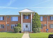 Thumbnail 11 of 12 - A red brick building with a white door and windows.