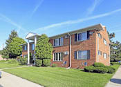 Thumbnail 9 of 12 - A red brick building with a white porch and a covered walkway.