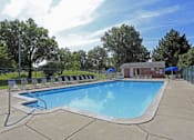 Thumbnail 7 of 12 - A large outdoor swimming pool surrounded by a fence and lounge chairs.