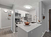 Thumbnail 1 of 25 - A kitchen with a white countertop and a bowl of fruit on it.