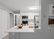 Thumbnail 4 of 25 - A kitchen with a white counter and a bowl of fruit on it.