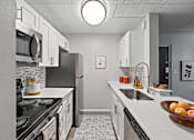 Thumbnail 5 of 25 - A kitchen with white cabinets and a black stove top.