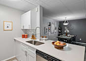 Thumbnail 2 of 25 - A kitchen with a marble countertop and a bowl of fruit on it.