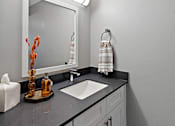 Thumbnail 12 of 25 - A bathroom with a sink, mirror, and towel rack.