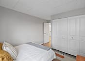 Thumbnail 15 of 25 - A bedroom with a bed, pillows, and a wooden floor.