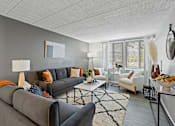 Thumbnail 9 of 25 - A living room with a grey couch, a white armchair, and a coffee table.