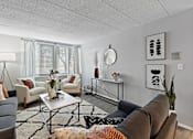 Thumbnail 10 of 25 - A living room with a brown couch, a white coffee table, and a rug with a geometric pattern.