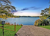 Thumbnail 91 of 116 - A pathway leads to a body of water with a sign on the left at The Waverly on the Lake - Belleville, MI Apartment , Michigan