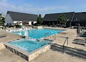 Thumbnail 27 of 39 - A large outdoor swimming pool with a hot tub and lounge chairs.