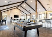Thumbnail 23 of 39 - A pool table is in the middle of a room with a bar and chairs.