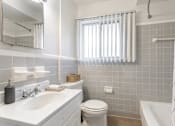 Thumbnail 12 of 17 - A white bathroom with a toilet, sink, and tub.