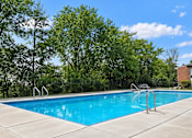 Thumbnail 13 of 17 - A swimming pool surrounded by trees and a fence.