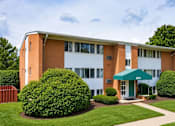 Thumbnail 15 of 17 - A building with a green awning and bushes in front.