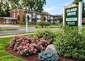 Thumbnail 17 of 17 - A sign for Island Drive Apartments stands in front of a building.