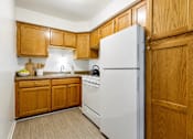 Thumbnail 2 of 17 - A kitchen with wooden cabinets and a white refrigerator.