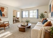 Thumbnail 7 of 17 - A living room with a brown leather chair and a white sofa.