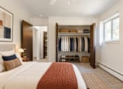 Thumbnail 9 of 17 - A bedroom with a large bed and a closet with clothes hanging.