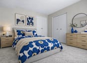 Thumbnail 22 of 87 - Bedroom with bold floral bedding and round mirror at Village Club of Farmington Hills Apartments, Farmington Hills, MI