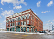 Thumbnail 20 of 21 - A red brick building with arched windows and a sign that says "The Brownstone".