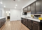 Thumbnail 3 of 18 - an open kitchen with dark wood cabinets and white countertops and a living room
