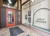 Thumbnail 5 of 18 - The front of the Howes Building is shown with a red door and a glass window.