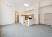 Thumbnail 6 of 18 - A spacious living area with a kitchen in the background.
