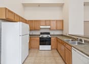 Thumbnail 11 of 18 - A kitchen with a white refrigerator, black stove, and wooden cabinets.