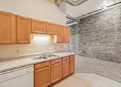 Thumbnail 5 of 21 - A kitchen with wooden cabinets and a brick wall.