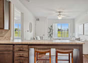 Thumbnail 21 of 23 - A kitchen with a marble countertop and wooden chairs.