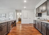 Thumbnail 20 of 23 - A kitchen with dark wood cabinets and a white counter top.