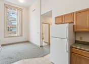 Thumbnail 12 of 18 - A white refrigerator sits in a kitchen with wooden cabinets.