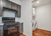 Thumbnail 19 of 23 - A kitchen with a stove top oven and a washing machine.