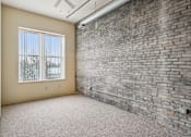 Thumbnail 8 of 21 - A room with a brick wall and a window with a view of trees.