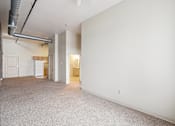 Thumbnail 9 of 21 - A large empty room with a carpeted floor and white walls.