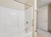 Thumbnail 14 of 21 - A white bathroom with a tub and a door.