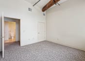 Thumbnail 11 of 21 - A room with a carpeted floor and a doorway leading to a bathroom.