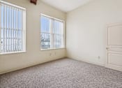 Thumbnail 13 of 21 - A room with a door, two windows, and a carpeted floor.