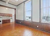 Thumbnail 8 of 25 - A large empty room with wooden floors and a view of the outside through the windows.