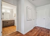 Thumbnail 9 of 23 - A bathroom with a wooden floor and white walls.