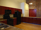 Thumbnail 24 of 27 - A kitchen with wooden cabinets and a black fridge.