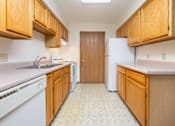 Thumbnail 3 of 12 - A kitchen with wooden cabinets and a white fridge.