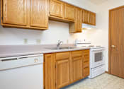 Thumbnail 4 of 12 - A kitchen with wooden cabinets and white appliances.